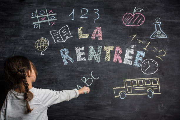 Back to school Little girl writing “La rentrée” multicoloured words blackboard (Back to School in french language . She is also drawing a school bus, an apple, a mathematical formula and other school related symbols. french language photos stock pictures, royalty-free photos & images
