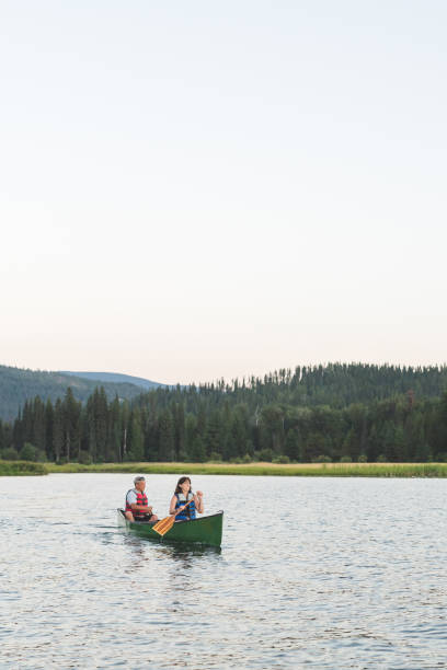 istock Senior couple canoeing together around a forested lake. 1016287154