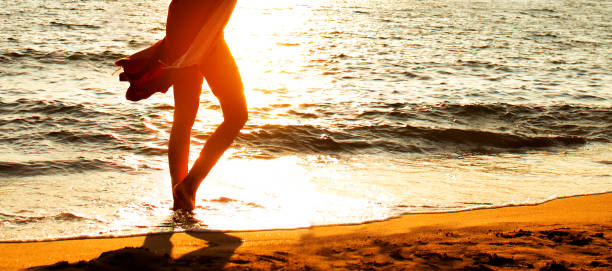 istock woman walking on the beach at sunset 1016293244