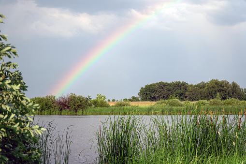 Rainbow over the lake and forest against a cloudy sky
