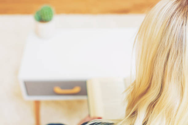 istock Happy young woman reading a book on her couch 1016314756