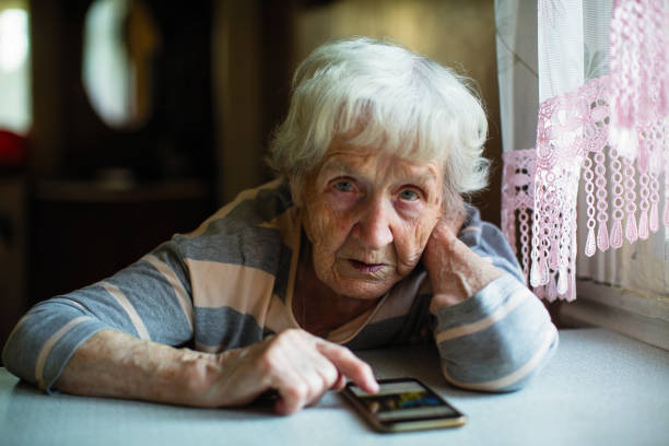 istock An elderly woman with a smartphone sitting at the table. 1016325048