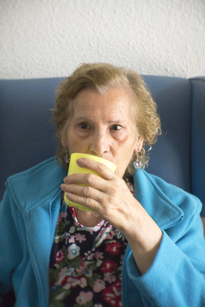 istock Older woman drinking water from a glass to hydrate 1016325374