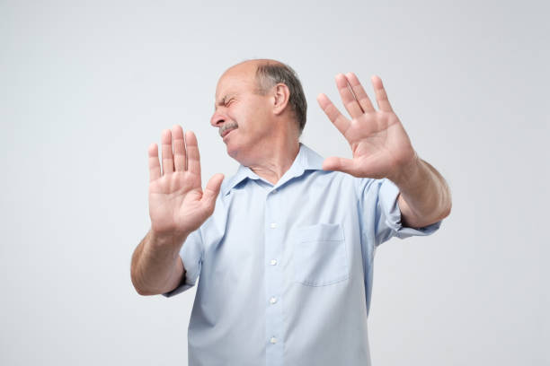 istock Displeased mature man refusing, stretching hands to camera over grey background. 1016328264