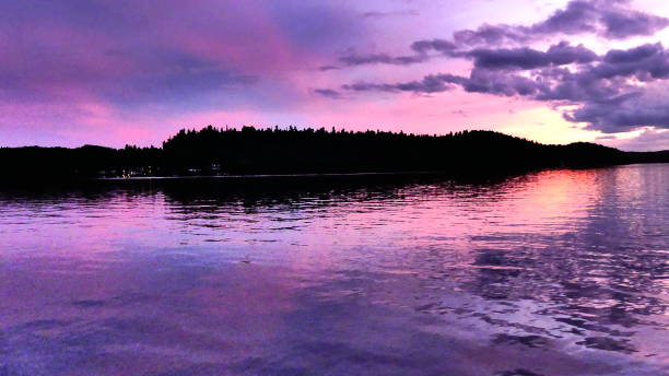 istock Pink and purple sun layer on the water with mountain silhouette 1016340708
