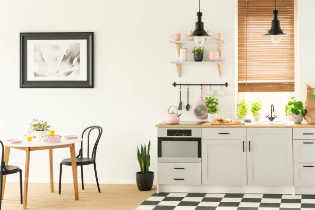 istock Industrial lamps and black dining chairs in a white kitchen interior with a modern oven and breakfast food 1016348416
