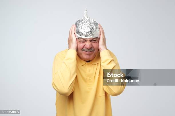 Caucasian Mature Man In A Tin Foil Hat Displeased Hiding From Outdoor Life Stock Photo - Download Image Now