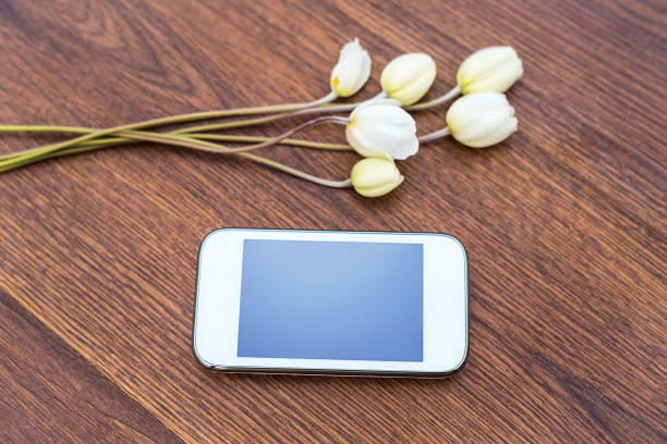 istock Mobile phone with white flowers on wooden background 1016462614