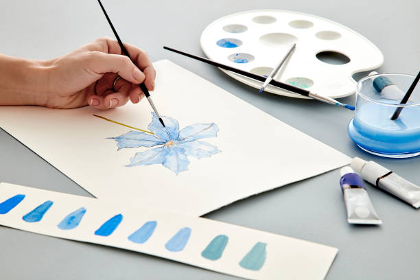 Woman painter coloring flower painting with watercolors stock photo