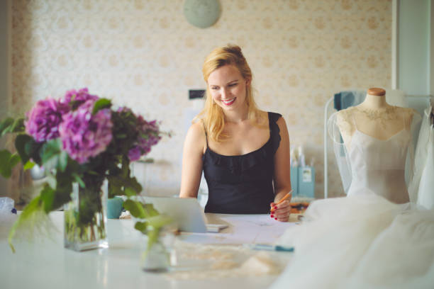 fashion designer is taking notes on a laptop - independence business women manual worker imagens e fotografias de stock