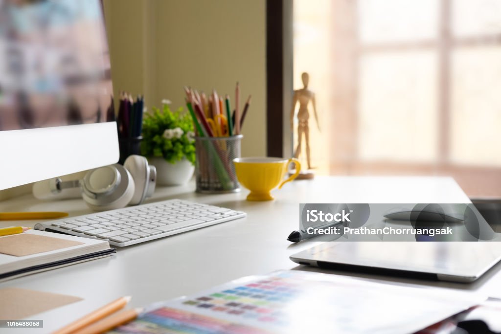 Side view Modern office workplace with digital tablet, notepad, colorful pencils, computer in morning. Desk Stock Photo