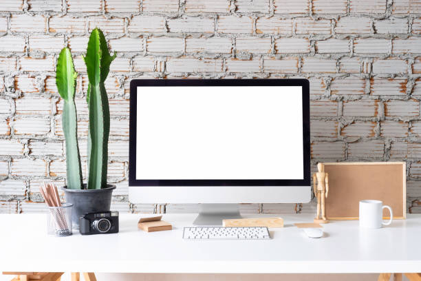 istock Workspace and Mock up Computer office with coffee mug, jar of pencil and notepad paper on white table and brick wall. 1016488296