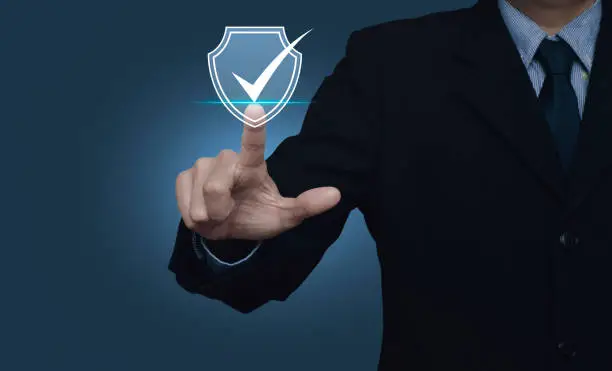 Businessman pressing security shield with check mark icon over gradient light blue background, Technology computer and internet cyber security  and anti virus concept