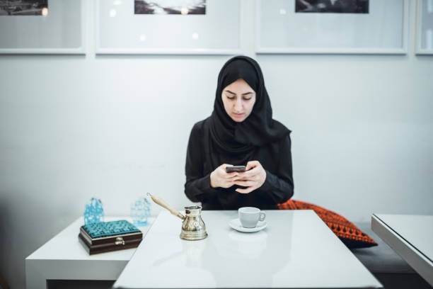 istock Muslim young woman at cafe, using mobile phone 1016494410