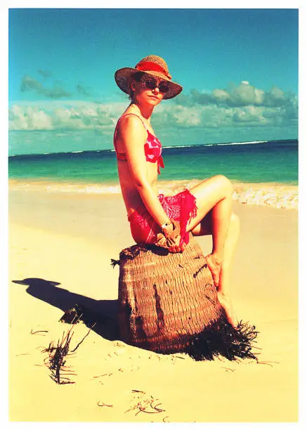 Young woman sitting in front of the camera in a beach at the caribbean sea.