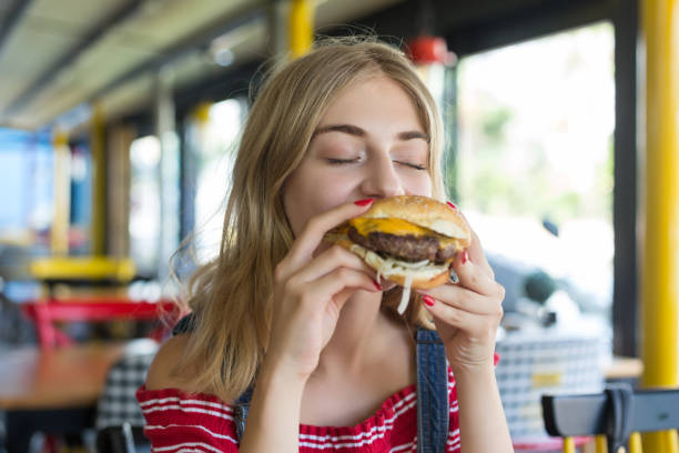 woman eating a hamburger - burger hamburger food fast food imagens e fotografias de stock
