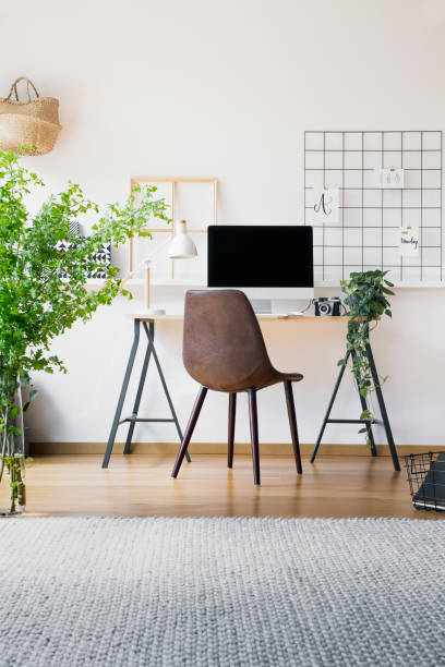 istock Inspirational organizer in a hipster workspace interior with a stylish, leather chair by a tall, industrial desk with a desktop computer 1016510112