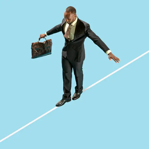 Business man on tightrope concentrate to walking isolated on blue background. Business, career, risk concepts