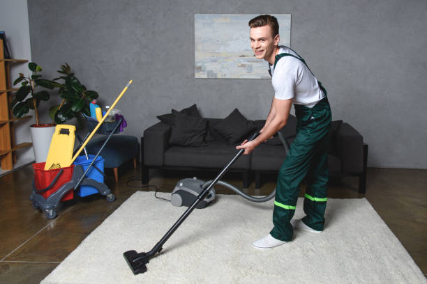 istock handsome young man cleaning white carpet with vacuum cleaner and smiling at camera 1016518278