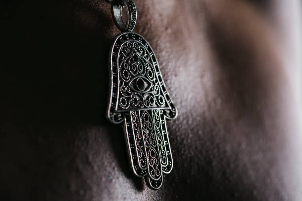 closeup of an old hamsa amulet, also known of the hand of fatima or the hand of mary, hanging from the neck of a man
