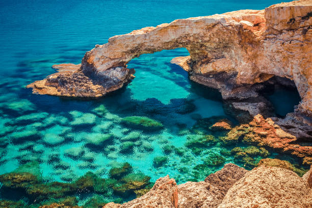 piękny naturalny łuk skalny w pobliżu ayia napa, cavo greco i protaras na cypryjskiej wyspie, morze śródziemne. legendarni miłośnicy mostów. niesamowite błękitne zielone morze i słoneczny dzień. kreatywne tonowanie podziału - greco roman zdjęcia i obrazy z banku zdjęć
