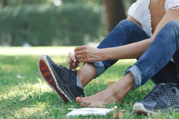 The girl takes off sneakers and rest barefoot on the grass in the park. Notepad and pencil - the concept of creative thinking and the search for new solutions.