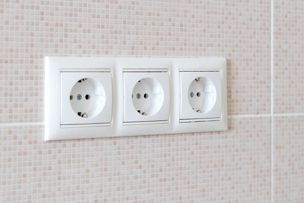 Row of power sockets on a ceramic tile wall stock photo