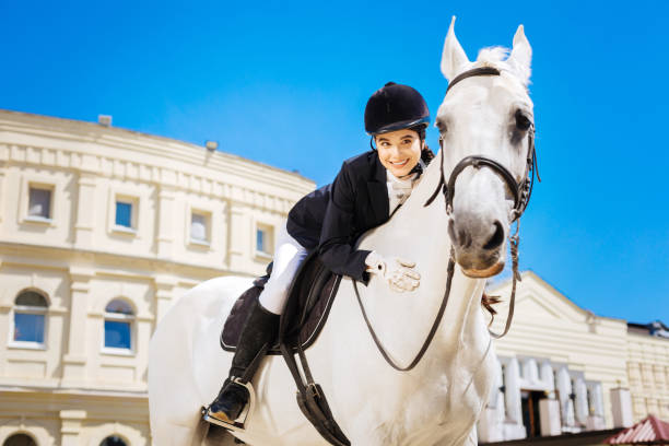 istock Black-eyed beaming female rider leaning on her devoted white horse 1016541946