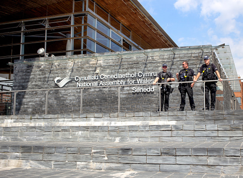 Cardiff, Wales - August 4th, 2018: Police officers standing guard outside the National assembly for Wales signage in Cardiff Bay, Cardiff, Wales, during the 2018  Eisteddfod
