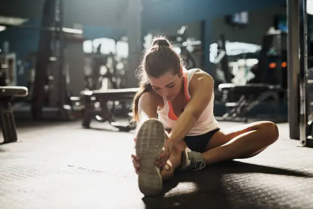 Shot of a young woman doing stretch exercises at the gym