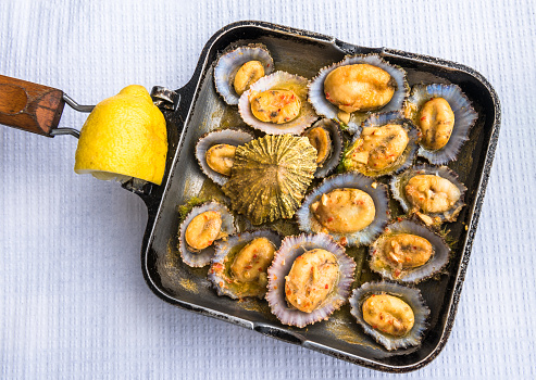 Grilled limpets in the pan served with lemon