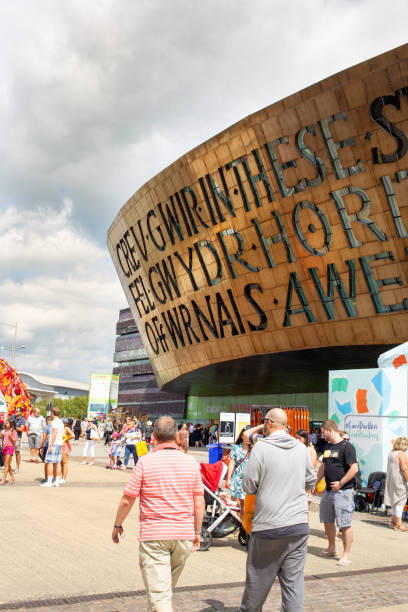 Visitors exploring the 2018 Eisteddfod walking around The Millennium Centre. Cardiff, Wales - August 4th, 2018: Visitors exploring the 2018 Eisteddfod walking around The Millennium Centre. It was built to celebrate the diversity of Welsh culture. It houses one large theatre and two smaller halls with shops, bars and restaurants. It's a popular area for visitors and tourist to the capital. cardiff wales stock pictures, royalty-free photos & images
