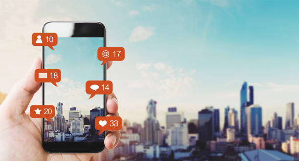istock Hand holding mobile smart phone, with notification icons and city background 1016579646