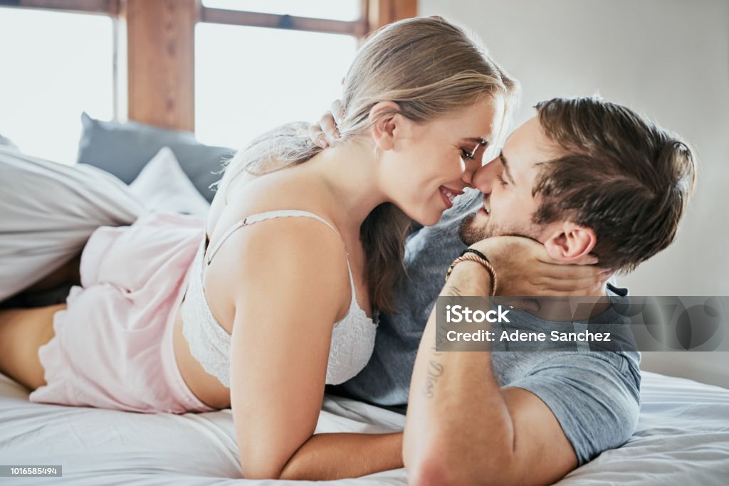You make me want to stay in bed all day Shot of an affectionate young couple lying in bed Bed - Furniture Stock Photo