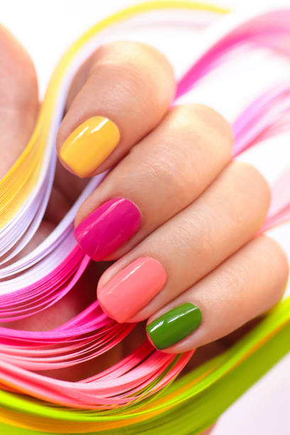 Multi-colored manicure. Multi-colored manicure with pink, green, yellow and peach nail polish close-up.Summer bright manicure on short nails. yellow nail polish stock pictures, royalty-free photos & images