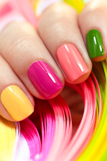Multi-colored manicure. Multi-colored manicure with pink, green, yellow and peach nail polish close-up.Summer bright manicure on short nails. yellow nail polish stock pictures, royalty-free photos & images