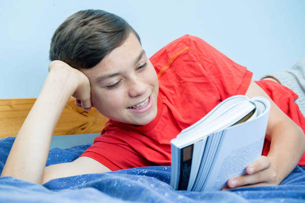 istock Caucasian teenage boy reading a book 1016598902