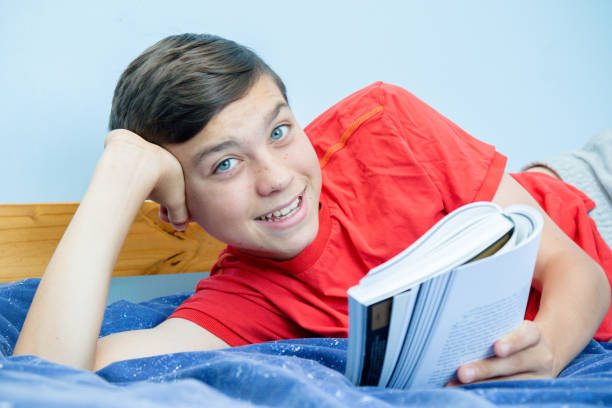 istock Caucasian teenage boy reading a book 1016598946