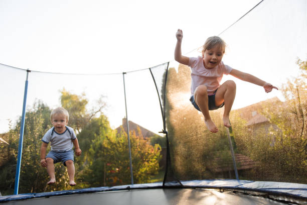 Kids jumping high on trampoline Siblings having fun together outside on trampoline real life photos stock pictures, royalty-free photos & images