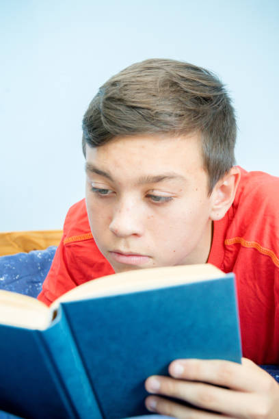 istock Caucasian teenage boy reading a book 1016602288