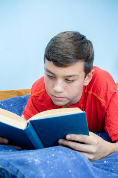 istock Caucasian teenage boy reading a book 1016602312