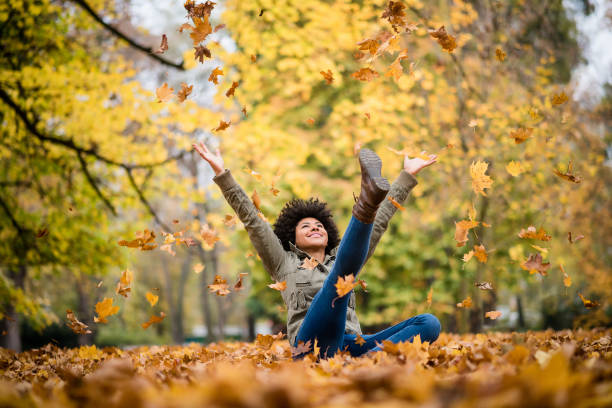 Autumn woman sitting with arms raised stock photo