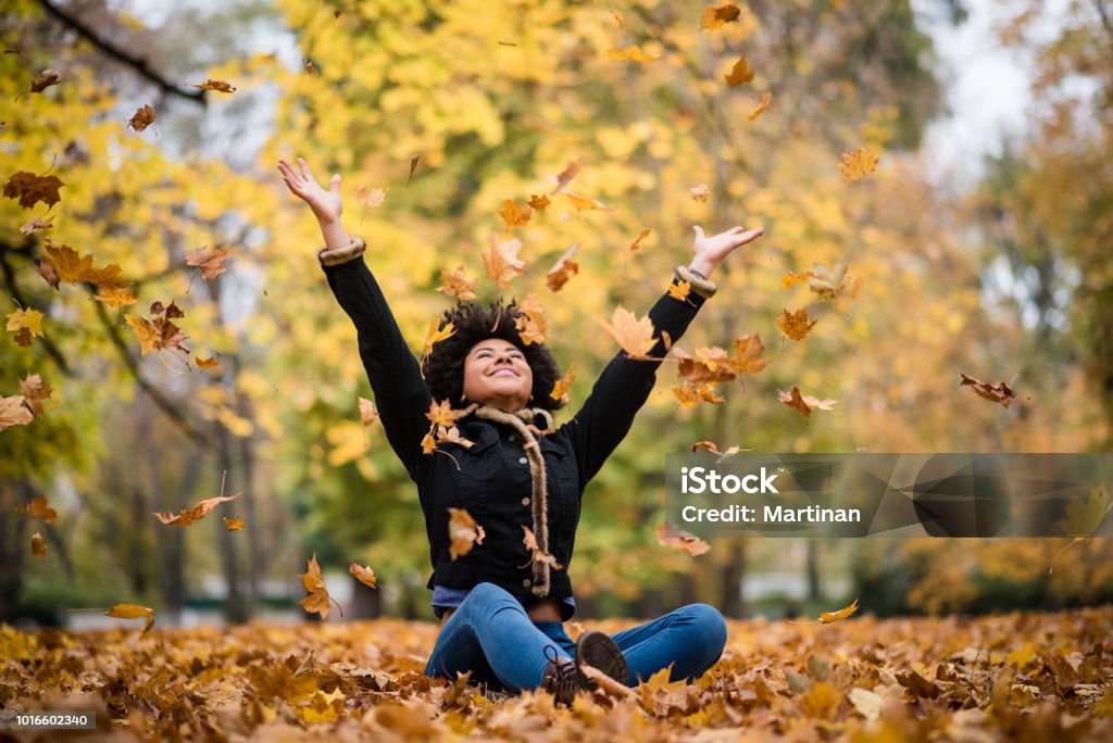 Joyous teen playing with dry maple leaves Happy woman in autumn park drop up leaves Autumn Stock Photo