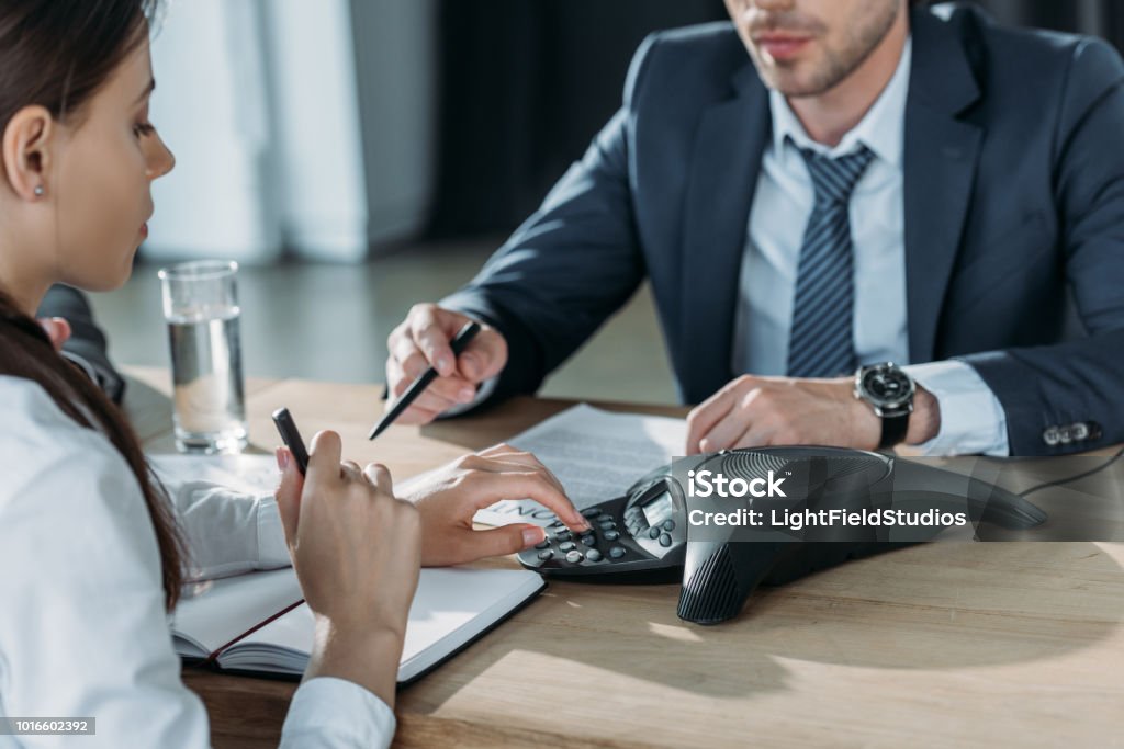 cropped shot of businessman and businesswoman using conference at modern office Conference Phone Stock Photo