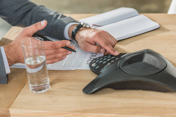 istock cropped shot of businessman using conference phone on table at office 1016602488