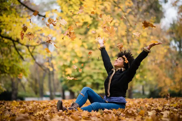 Woman throwing a bunch of autumn leaves, candid shot.