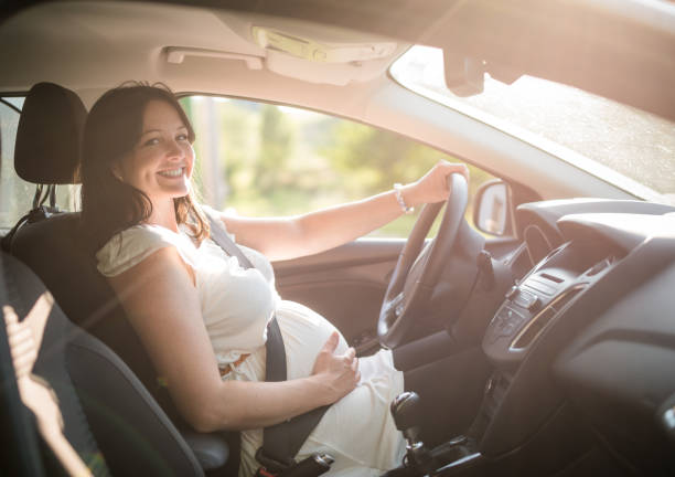 Beautiful smiling pregnant woman sitting in car - fotografia de stock