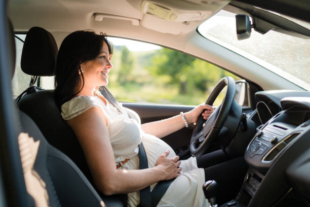 Pregnant woman driving her car, wearing seat belt. stock photo