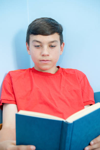 istock Caucasian teenage boy reading a book 1016605288