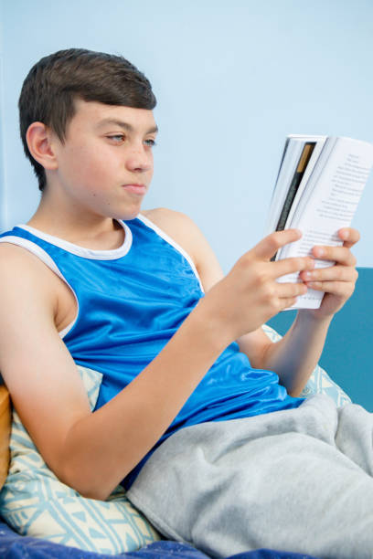 istock Caucasian teenage boy reading a book 1016605400